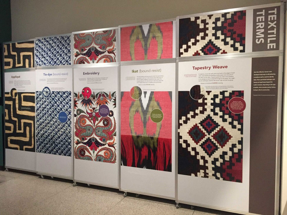Solid panels on wheels in a museum that show colorful textile patterns.